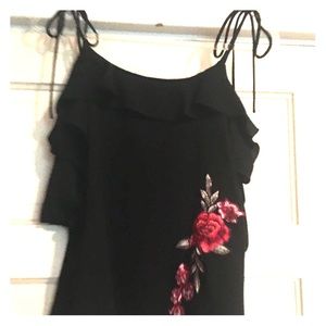 Black top with floral appliqué on side.